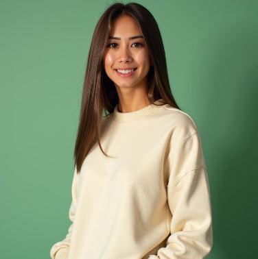 Woman wearing a cream-colored sweatshirt against a green background