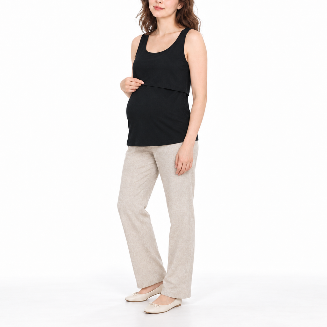 Angled front view of a pregnant model wearing a Black sleeveless maternity tank top with light-colored pants.