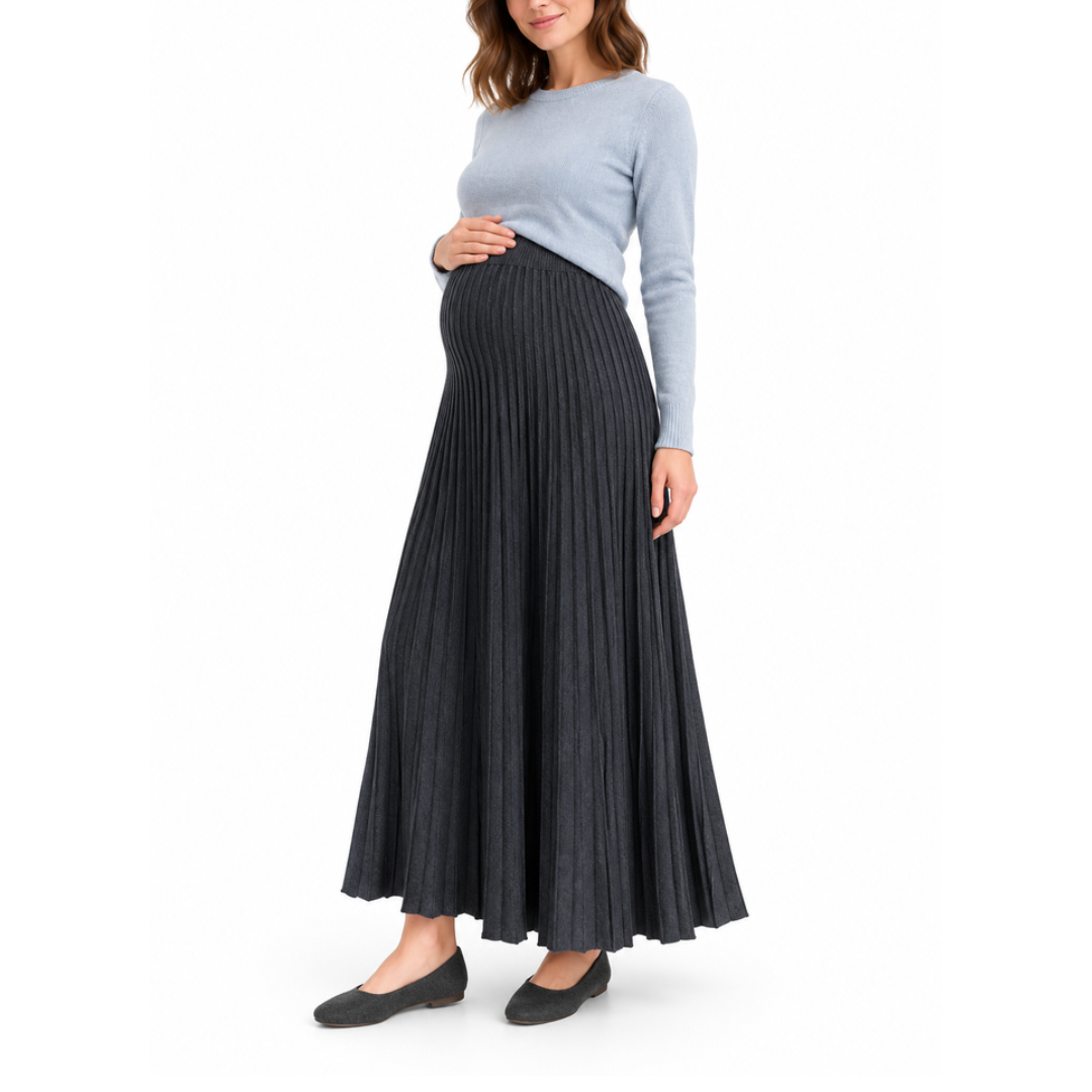Angled front view of a pregnant model wearing a black pleated maternity maxi skirt with a high waistband and light blue top.
