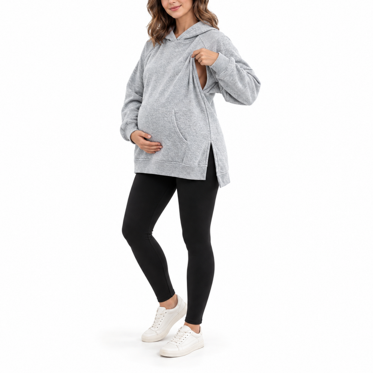 Angled front view of a pregnant model wearing a Light Gray maternity hoodie with black leggings and white sneakers.
