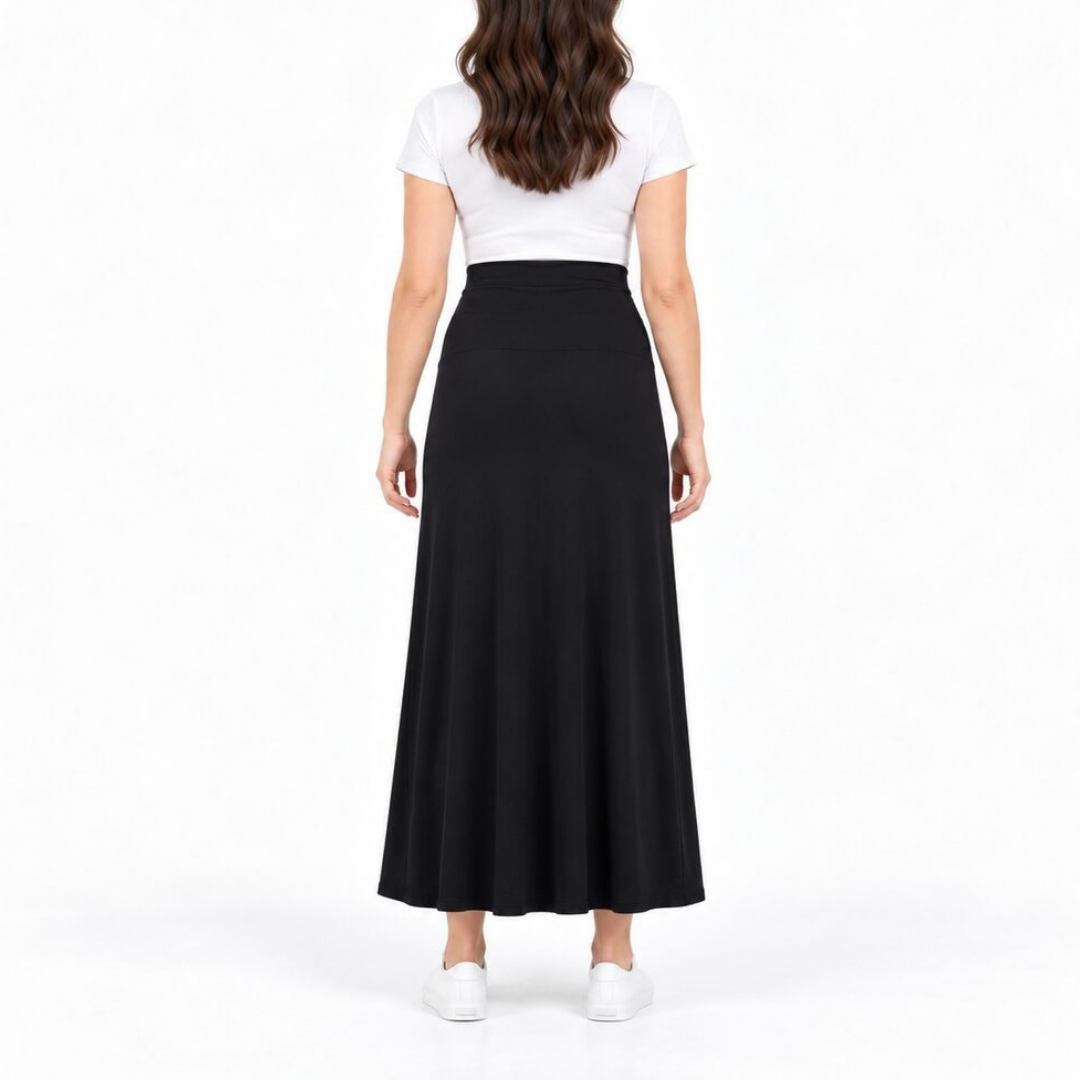 A woman shown from the back wearing a white short-sleeve crop top and a long black skirt, paired with white sneakers, against a plain white studio background.