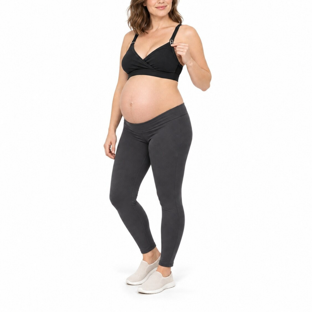 A pregnant model wearing a black maternity wrap bra and dark gray leggings, standing against a solid white background.