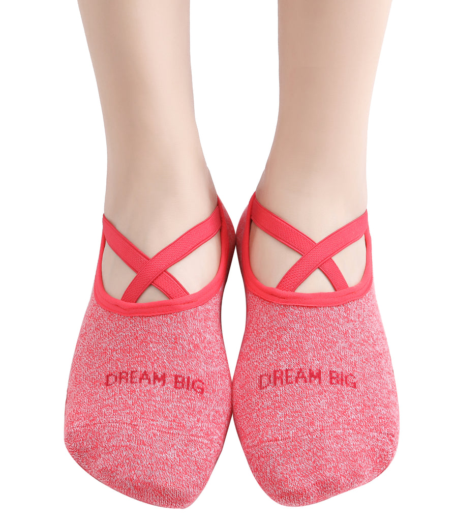 Red non-slip yoga socks with crisscross straps and "Dream Big" text, worn on feet, ideal for pilates and barre workouts.